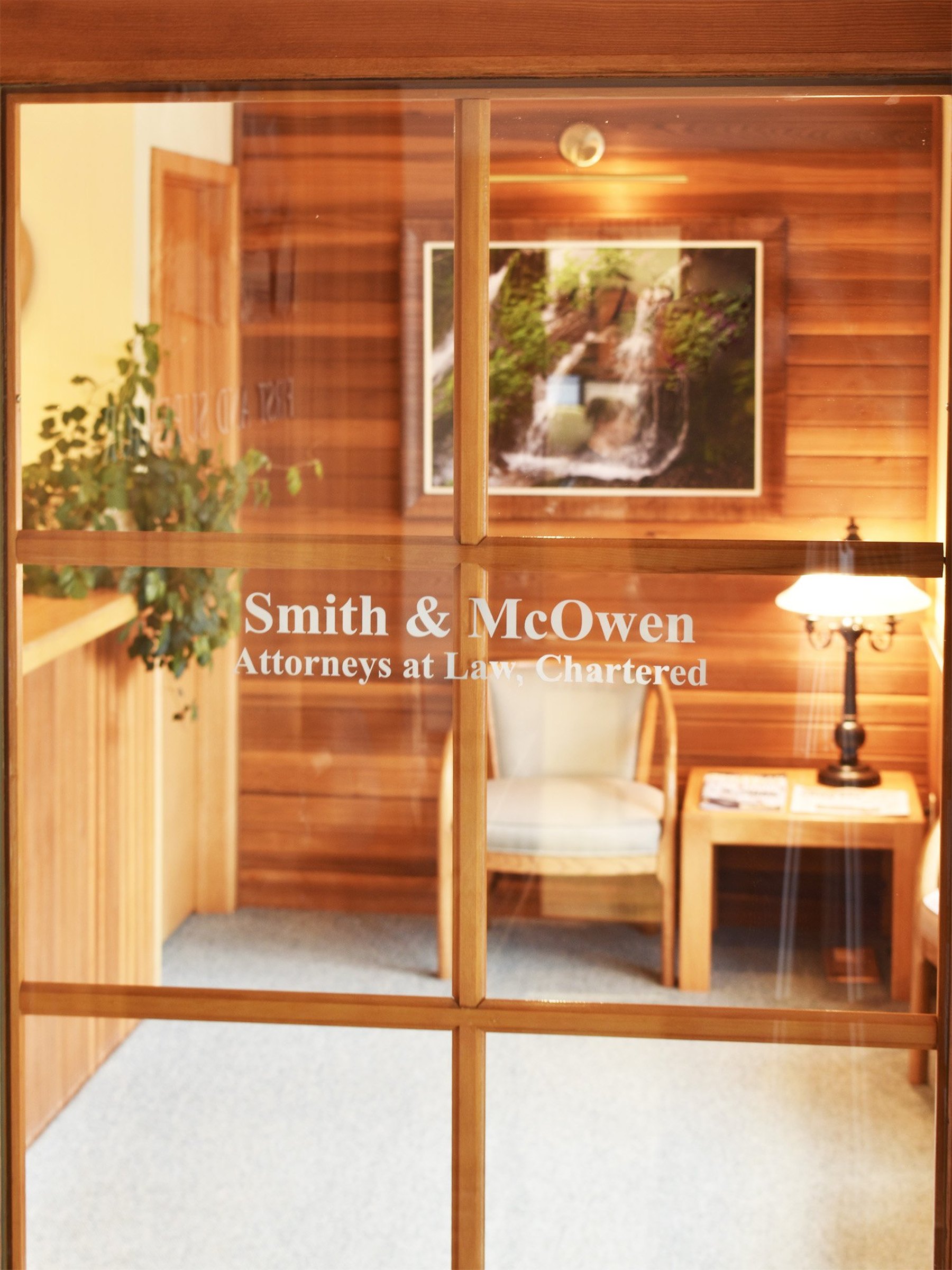 The cedar-framed glass door of Smith & McOwen, the firm's name etched on the pane, the waiting room lamplit behind it.